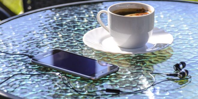 En kaffekopp och en Iphone på ett bord.