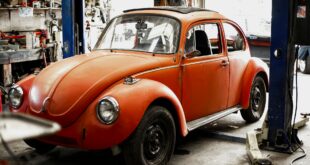 En orange röd VW Bubbla på verkstad