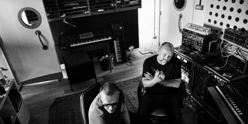 Svartvit bild på två män som sitter i en ljudstudio.