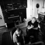 Svartvit bild på två män som sitter i en ljudstudio.