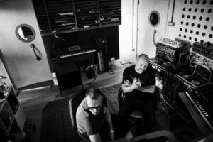 Svartvit bild på två män som sitter i en ljudstudio.