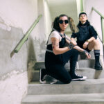 Lizzy och Emma i The Guilt sitter i en betongtrappa.