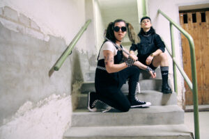 Lizzy och Emma i The Guilt sitter i en betongtrappa.