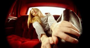 Ung kvinna med attityd och långt hår sitter i baksätet på en bil.